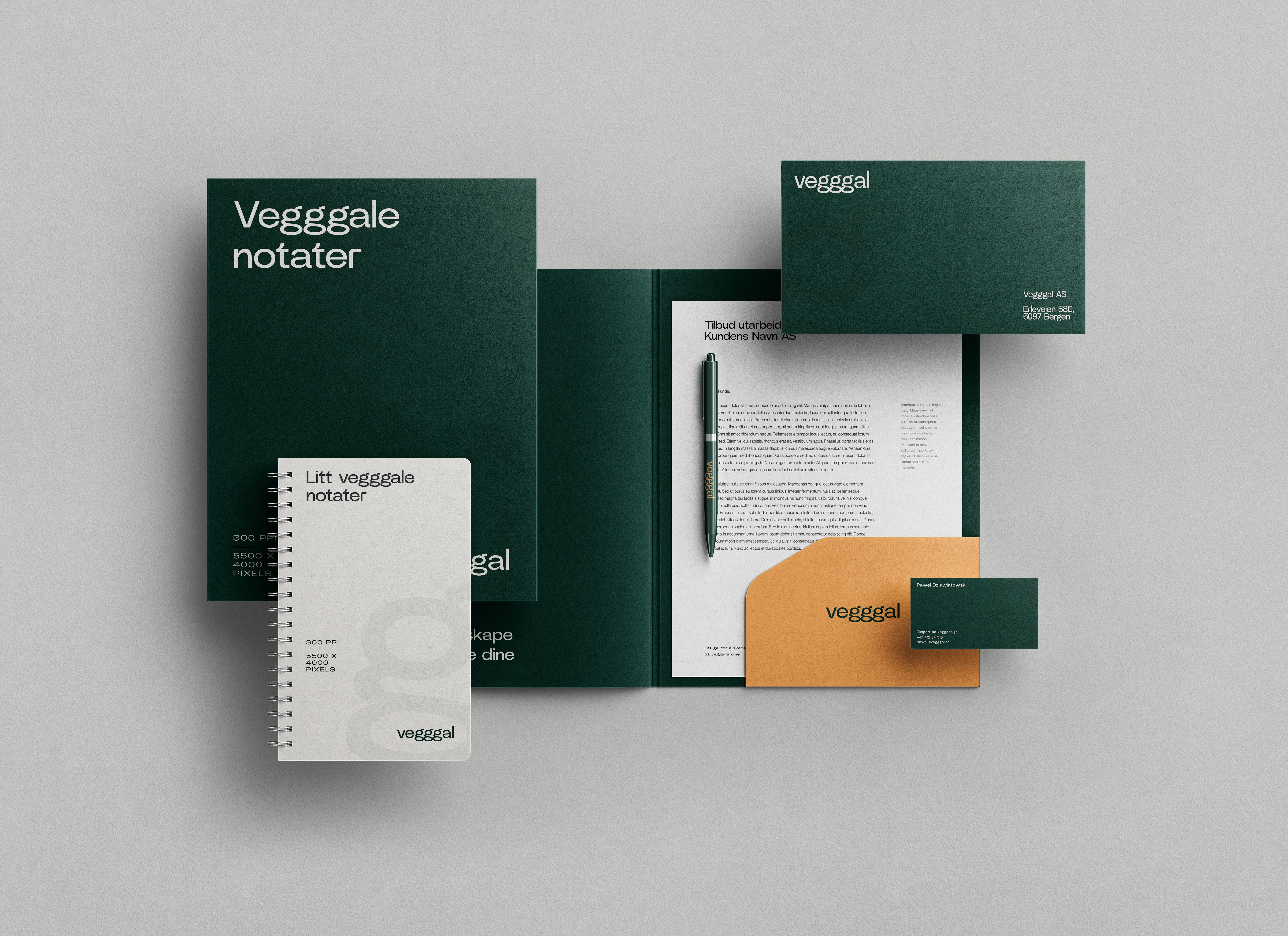 Sett med kontorartikler inkludert notatbøker, brevark, konvolutt, visittkort og penn i mørkegrønn og beige med merket Vegggal.