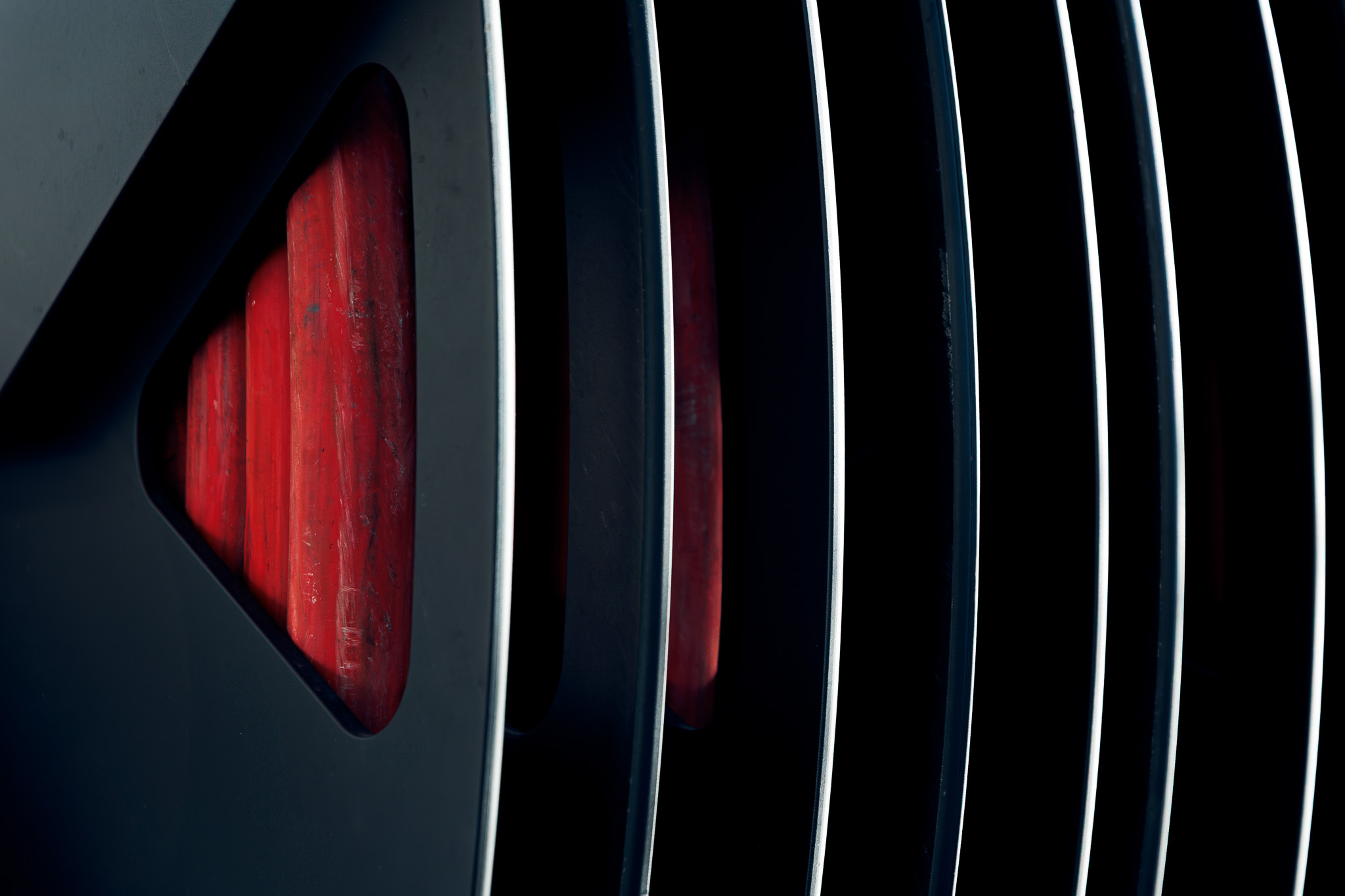 Close-up of a black car grille with visible red components behind the slats.