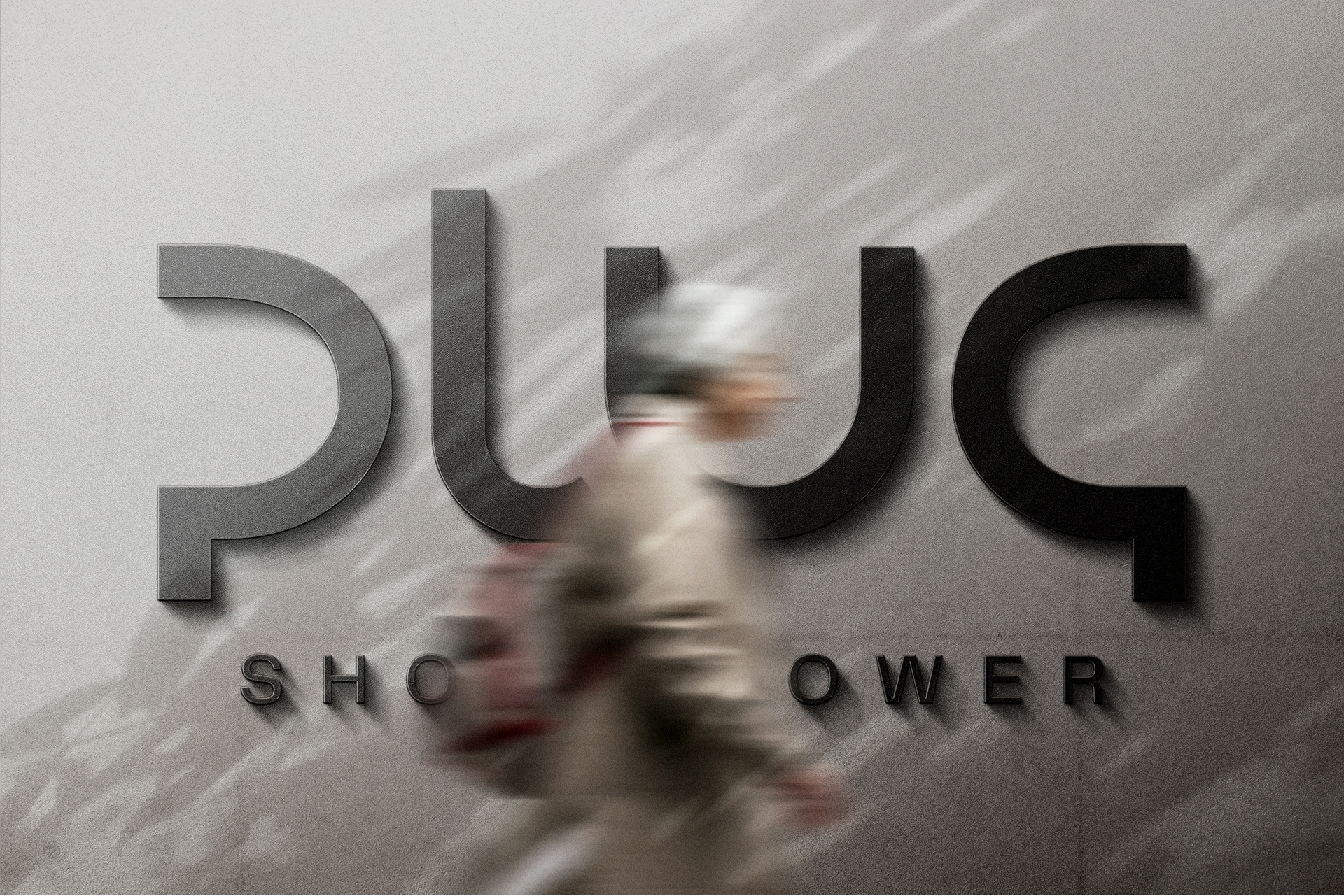 Blurred person walking past a wall sign with large black letters spelling 'PLUG' and smaller text below.
