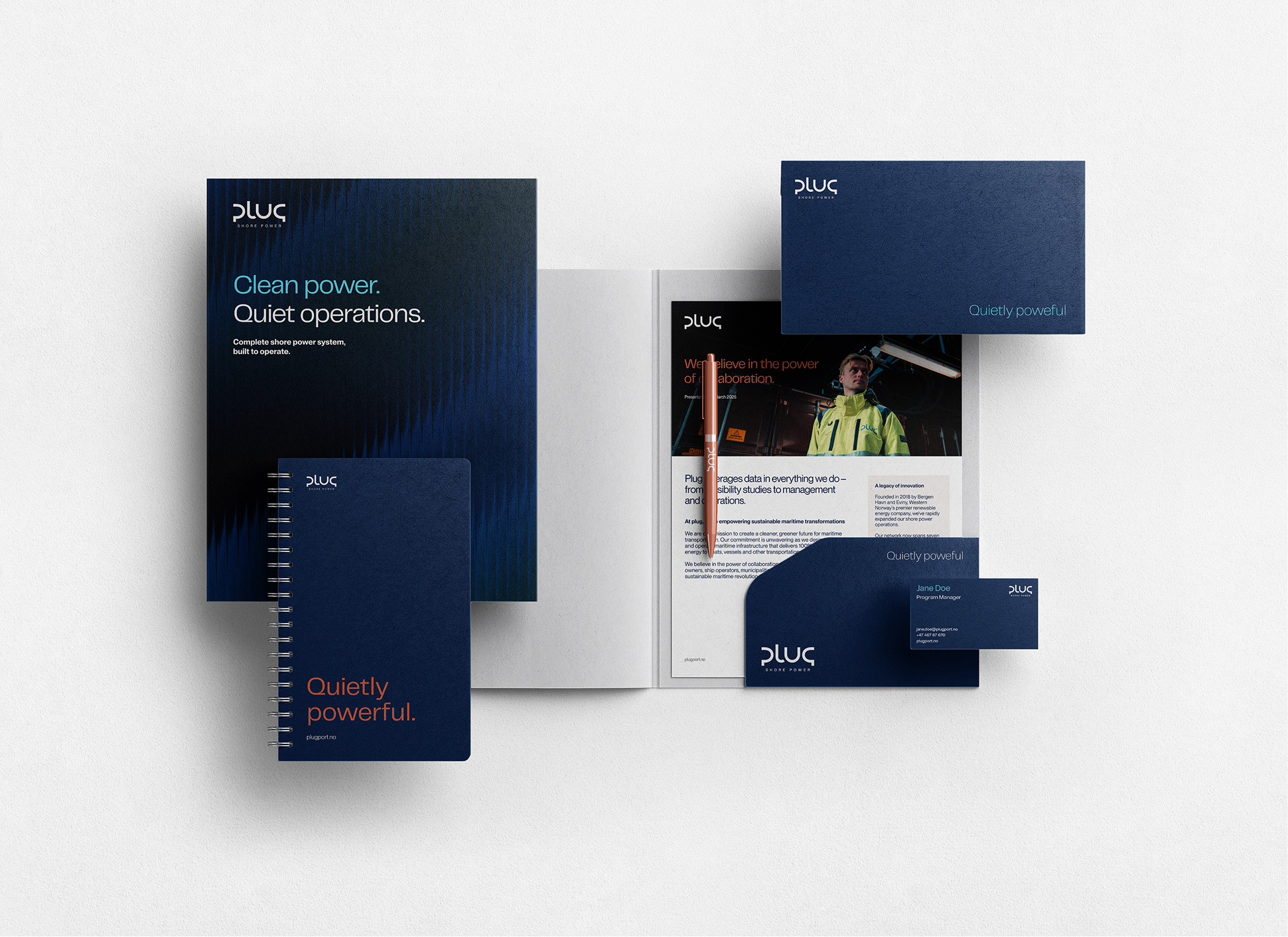 Branding stationary set including brochure, notebook, envelope, business card, and pen in navy blue with white and orange text reading Clean power, Quiet operations, and Quietly powerful.