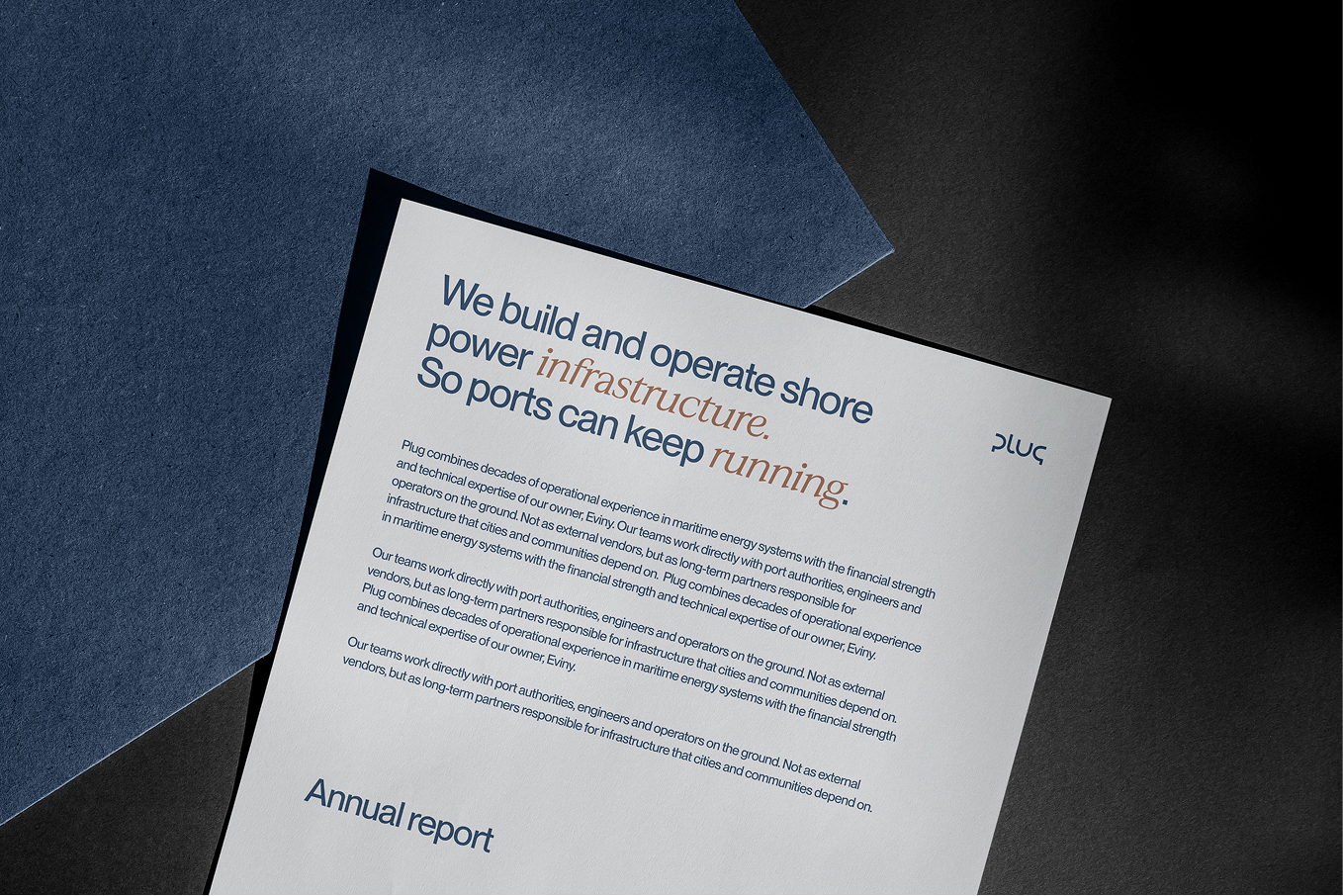 Close-up of a letterhead titled 'Annual report' with text about building and operating shore power infrastructure for ports, placed on a dark textured surface.
