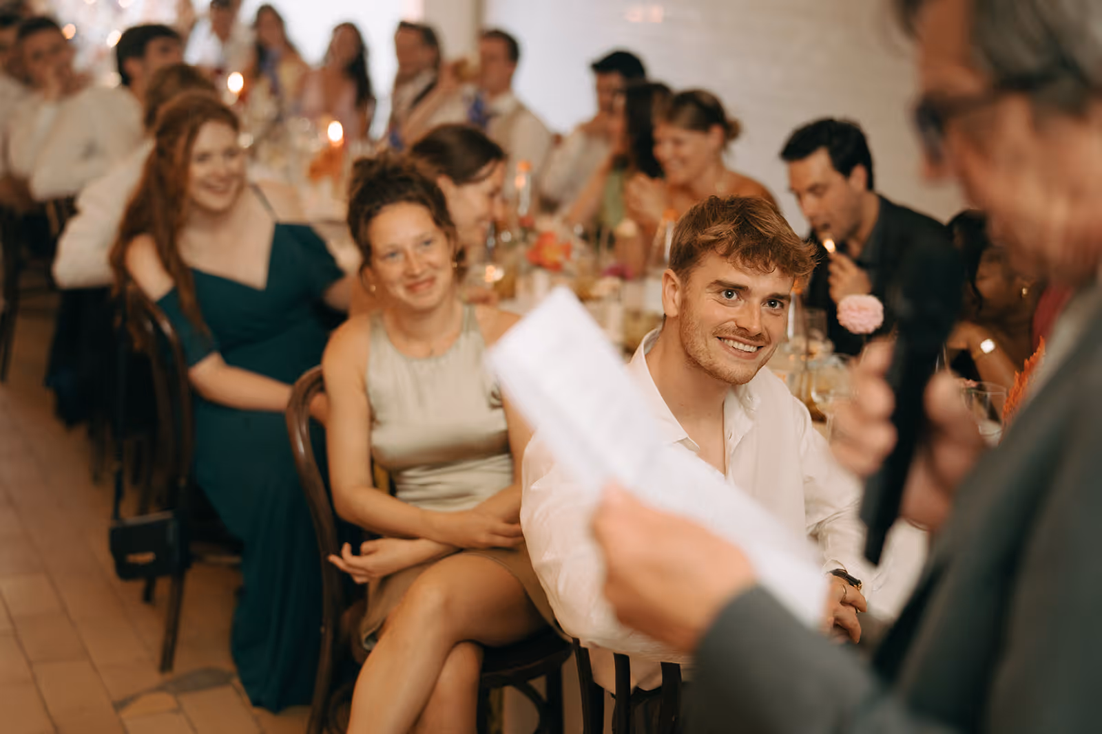 Guests attentively listening to a speech at a formal dinner event with softly lit tables.