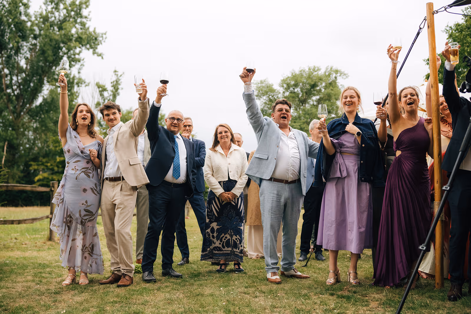 Group of people outdoors toasting with wine glasses in a celebratory gathering.