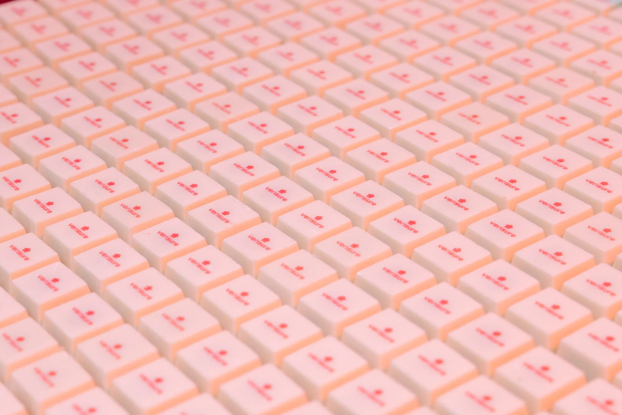 Close-up of many white computer keys with red text and logo reading 'versure' arranged in rows.