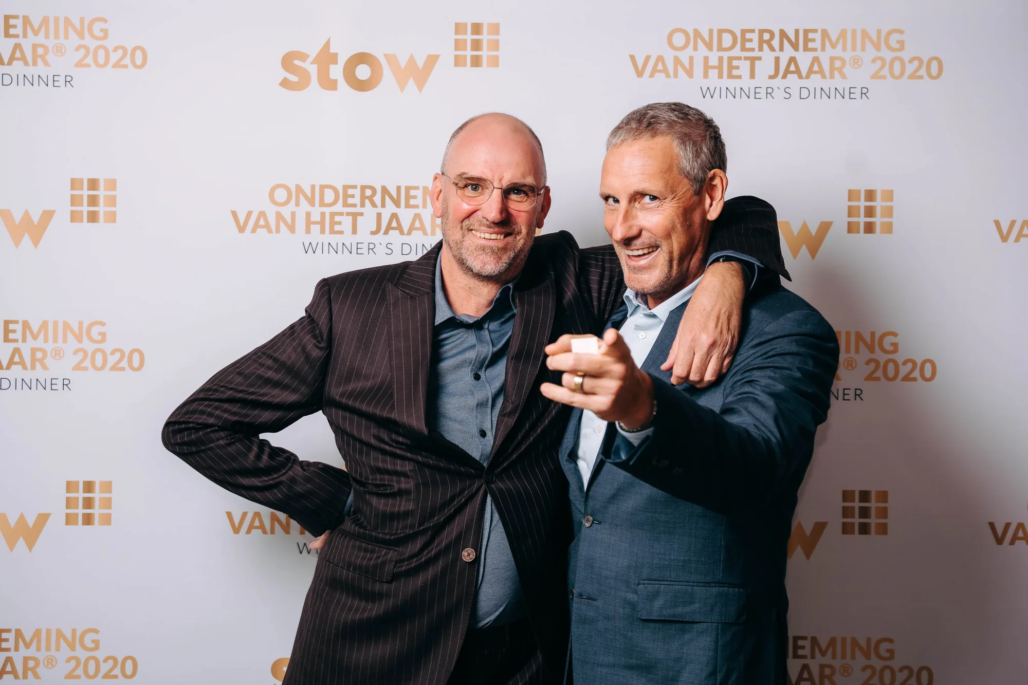 Two middle-aged men in suits smiling and posing together at the Onderneming Van Het Jaar 2020 winner's dinner event.