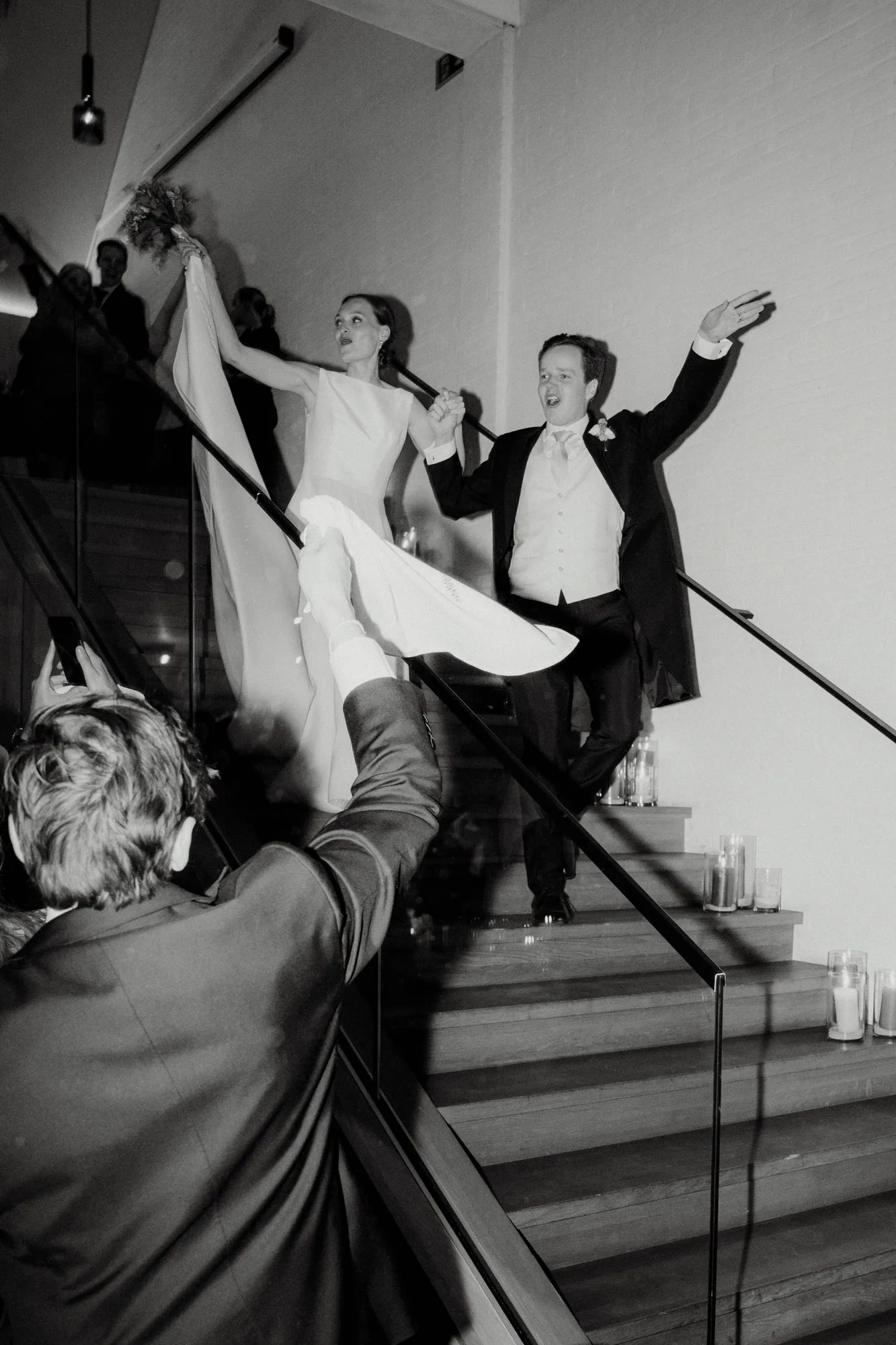 Bride and groom joyfully descending a staircase while holding hands at their wedding reception.