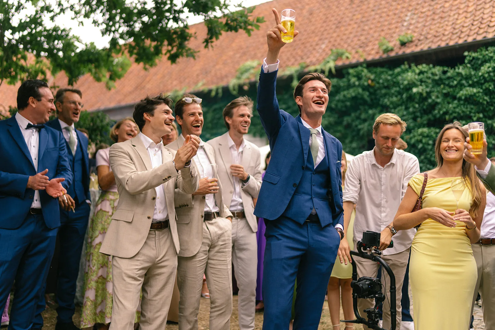 Group of well-dressed people outdoors smiling and raising glasses in a celebratory toast.