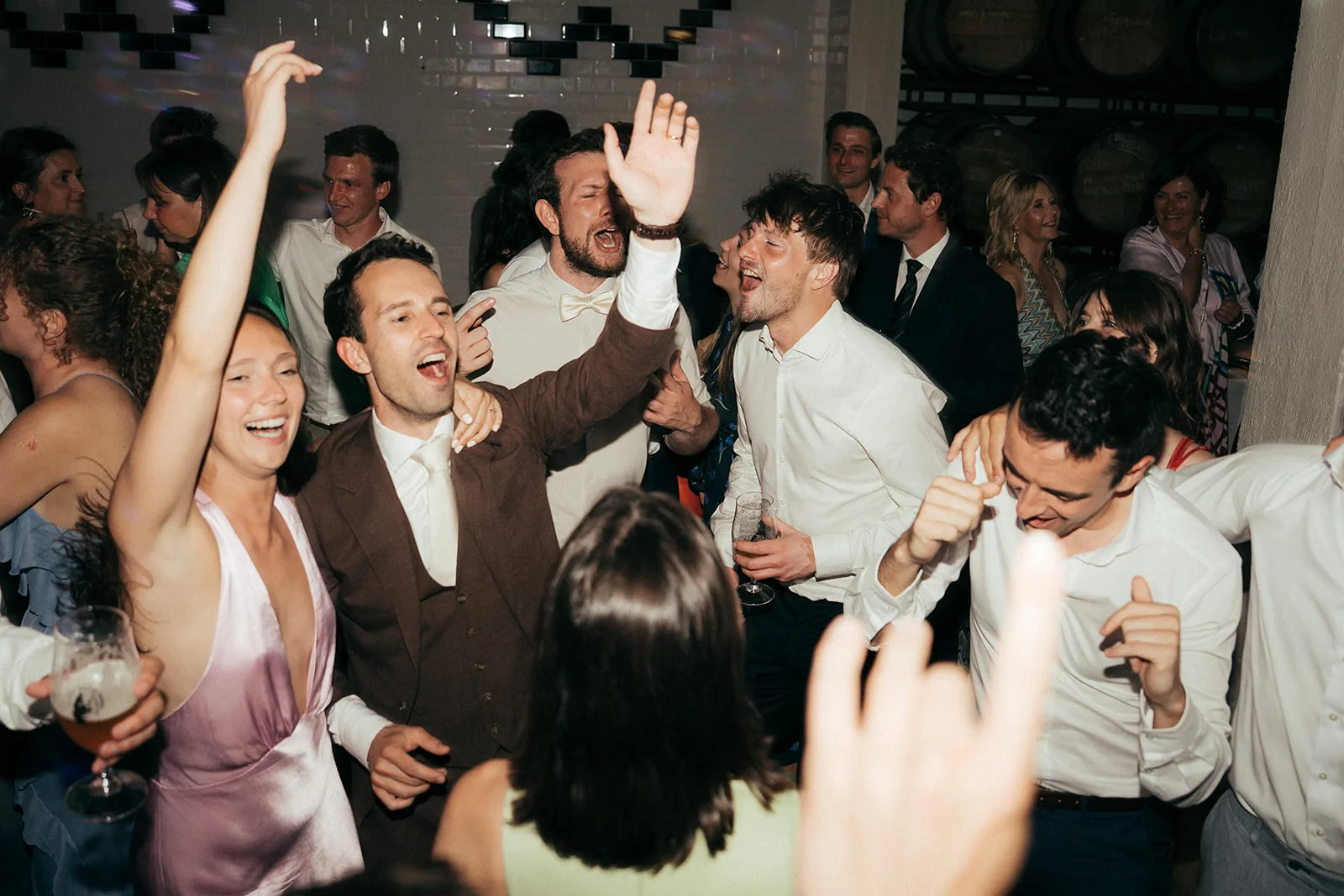Group of people dancing and singing at a lively party or celebration indoors.