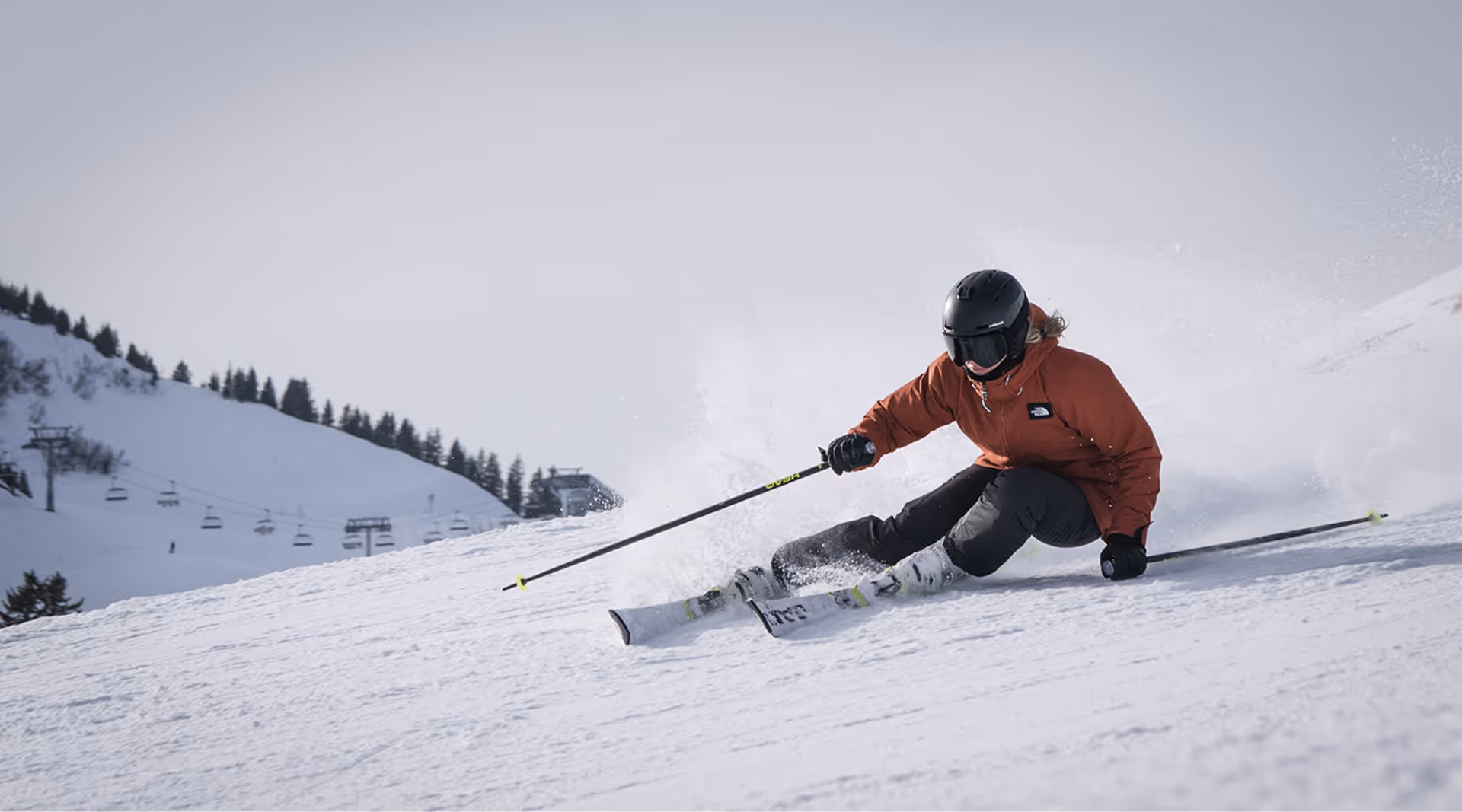 Skier in action on a snowy slope during a winter stay at The Swift Water hotel, featuring ski lifts in the background.