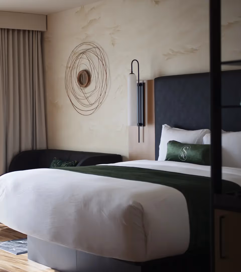 Elegant lounge at The Swift Water hotel featuring green velvet armchairs, wooden flooring, and a modern chandelier.