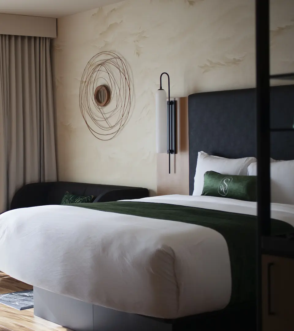 Elegant lounge at The Swift Water hotel featuring green velvet armchairs, wooden flooring, and a modern chandelier.