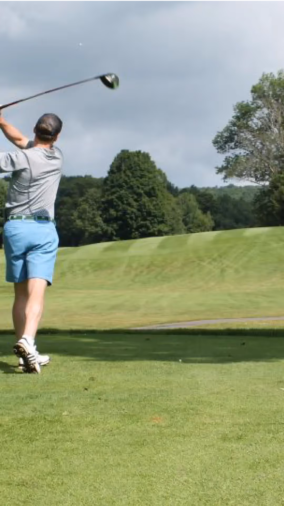 A golfer teeing off on a lush green golf course near The Swiftwater Hotel, showcasing the premium sports and leisure activities available for guests.