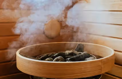 Steaming hot lava stones in a traditional wooden bucket at The Swiftwater hôtel, showcasing a relaxing spa and wellness atmosphere.