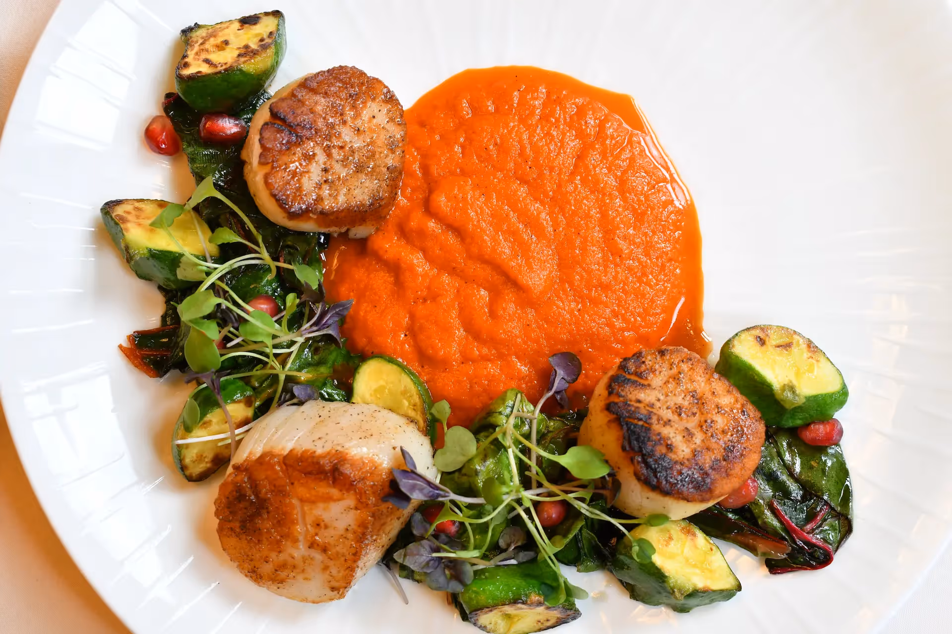 Pan-seared scallops served with red pepper puree, roasted Brussels sprouts, and fresh microgreens at The Swiftwater Hotel restaurant.