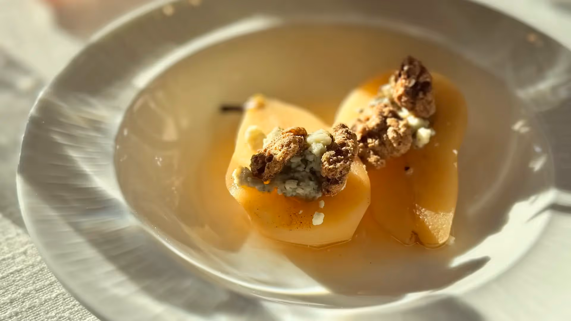 Elegant poached pears topped with walnuts and blue cheese crumbles, served in a white bowl at The Swiftwater hotel restaurant.