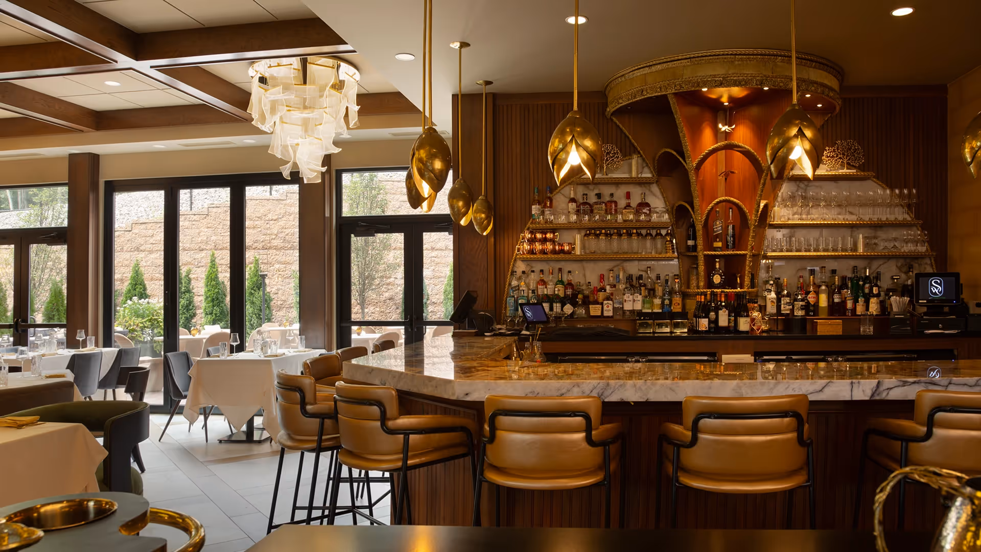 The elegant bar and dining area at The Swiftwater hotel, featuring luxurious design with gold light fixtures, marble countertops, and a warm ambiance.