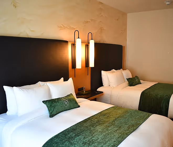 Close-up of premium white linens and signature green velvet pillows at The Swiftwater hotel.