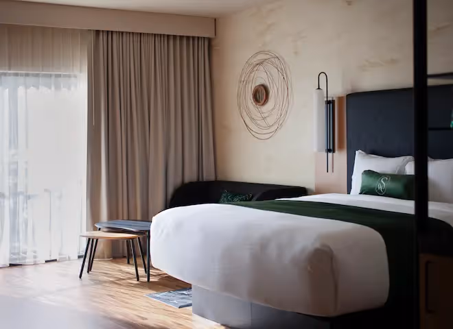Guest room and exterior view of Swan Hotel, a modern lodge-style property surrounded by landscaped flowers
