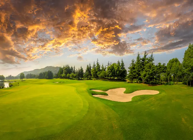 A golfer teeing off on a lush green golf course near The Swiftwater Hotel, showcasing the premium sports and leisure activities available for guests.