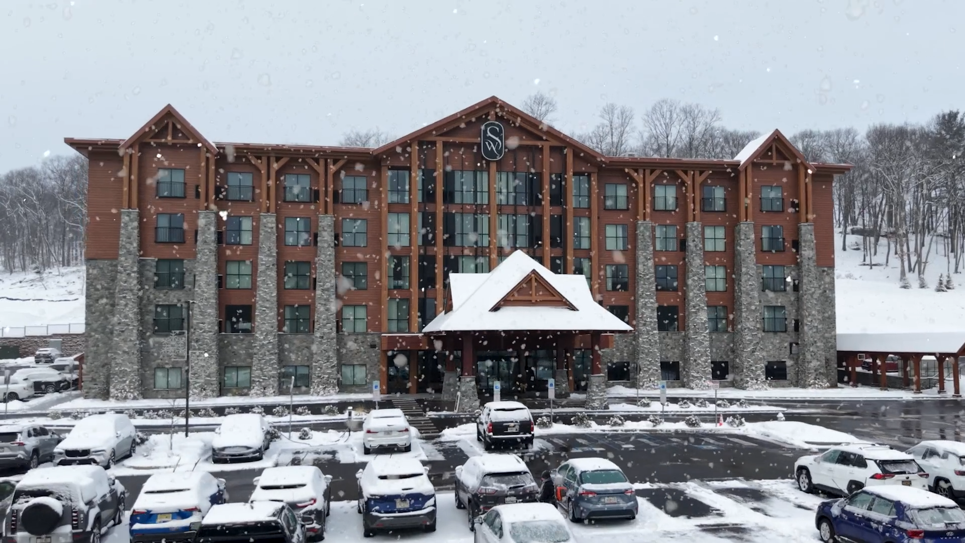 Wooden Swiftwater Hotel in a snowy setting, with a covered entrance, parked car, and trees partially in view.