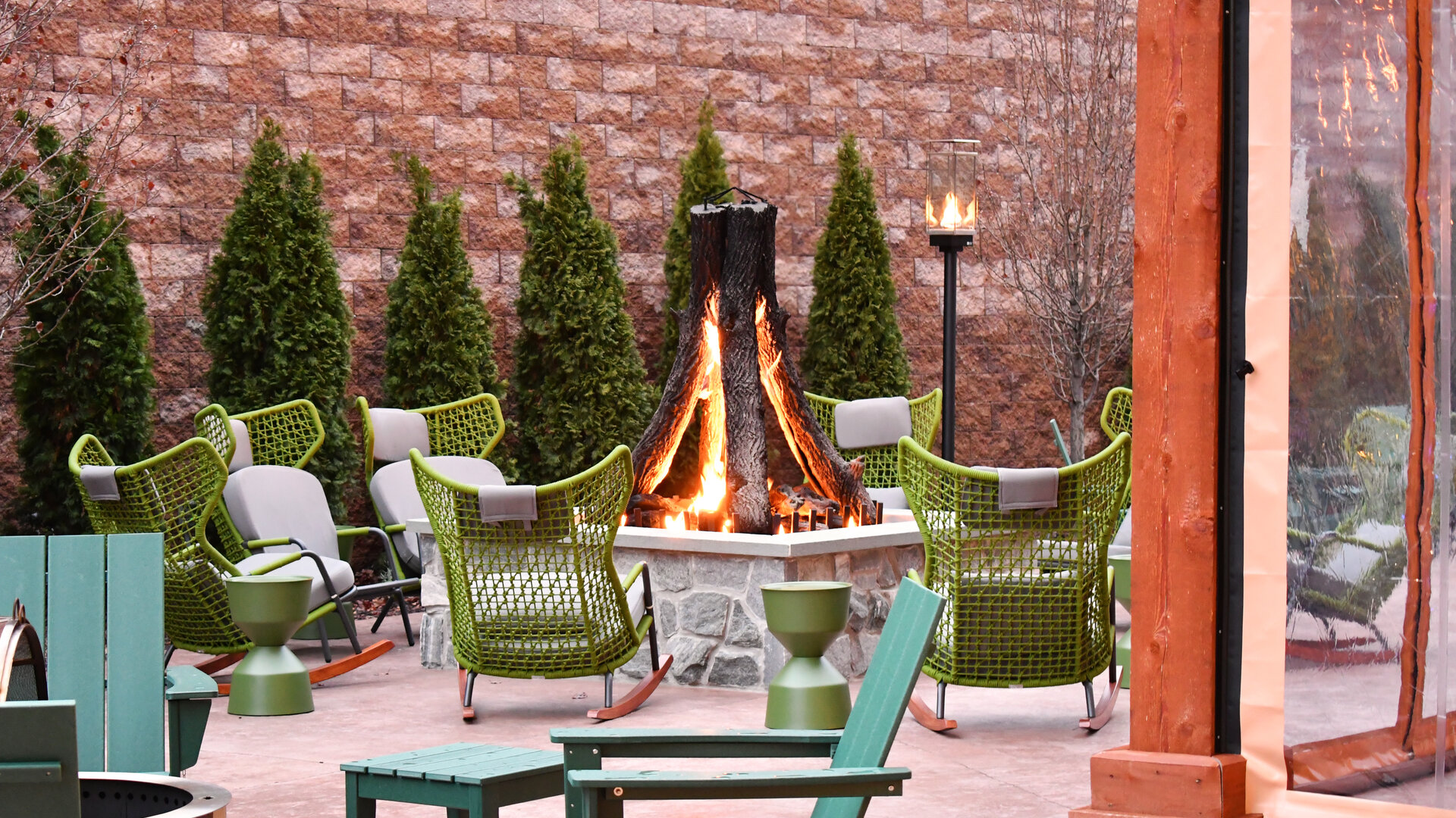 The Swiftwater's fire pit lounge patio with rocking chairs and evergreen landscaping, a popular evening spot for guests visiting Swiftwater, Pennsylvania.