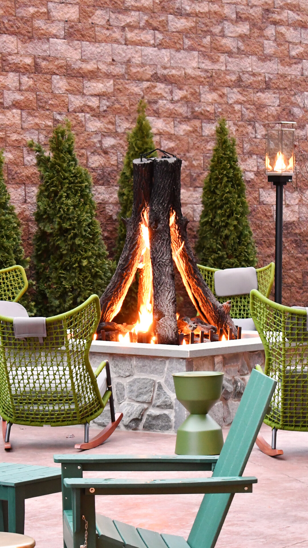 The Swiftwater's fire pit lounge patio with rocking chairs and evergreen landscaping, a popular evening spot for guests visiting Swiftwater, Pennsylvania.