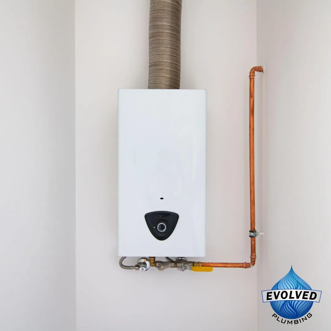 Wall-mounted white tankless water heater with copper piping and vent pipe above.