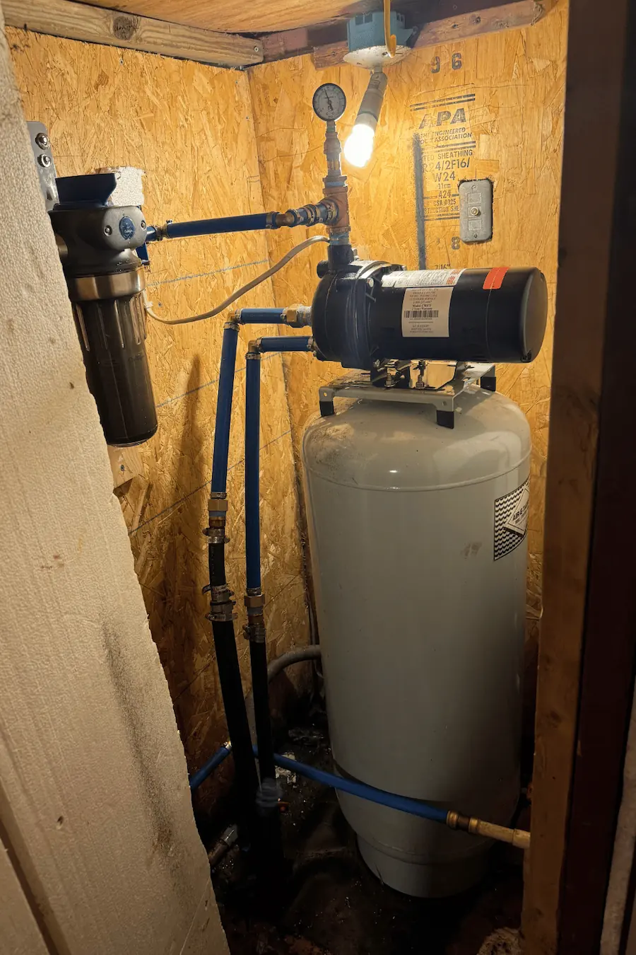 Close-up of an outdoor water pipe valve attached to a building wall with the Evolved Plumbing logo in the corner.