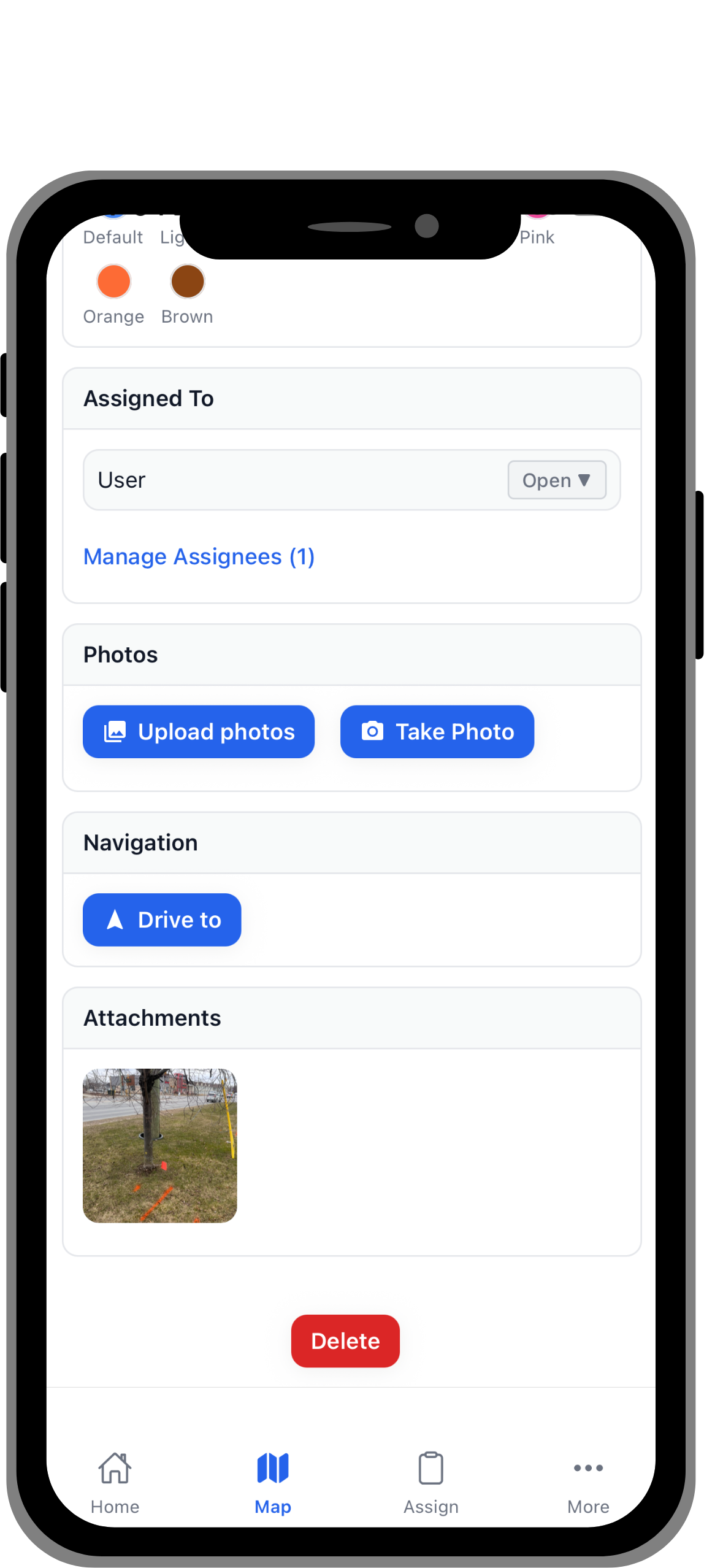 Mobile app screen showing assignment details with options to upload or take photos, drive to location, and a small attached photo of a tree with markings on grass.