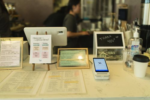 Cafe counter with a printed menu and a Dripos payment tablet