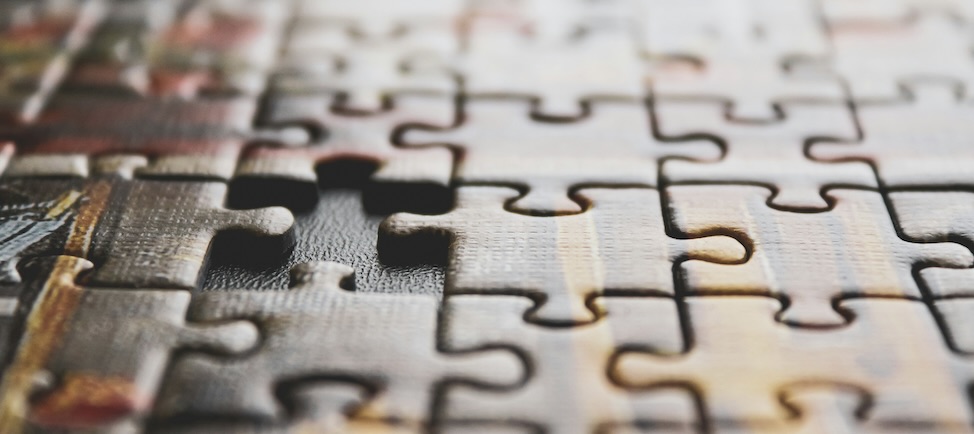 Close-up of a partially assembled jigsaw puzzle with one piece missing.