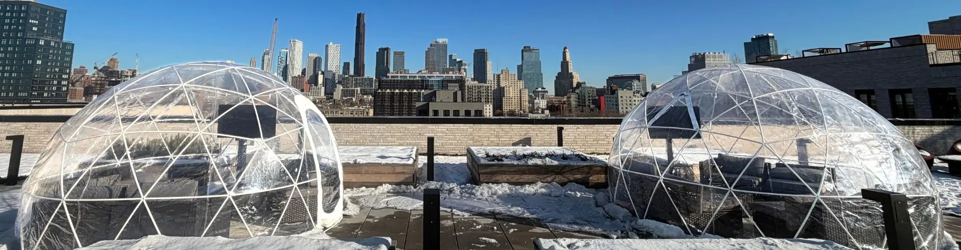 Two clear igloo rentals installed on a New York City rooftop for a commercial winter event