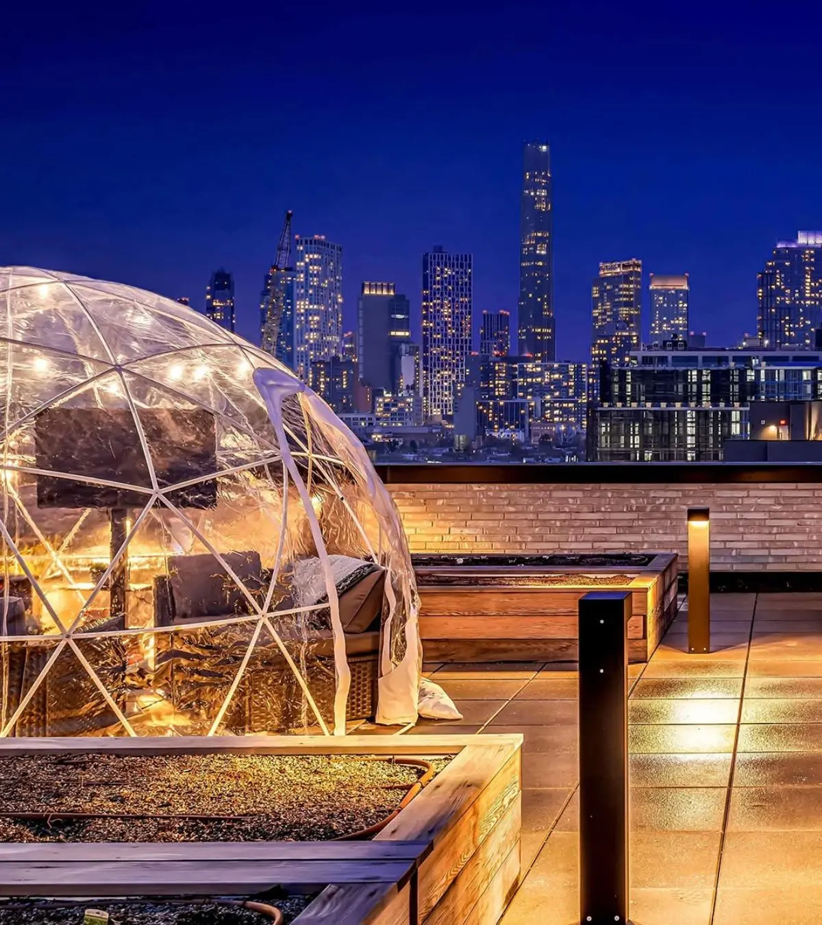 Heated igloo rental on a New York City rooftop terrace with Manhattan skyline views at night