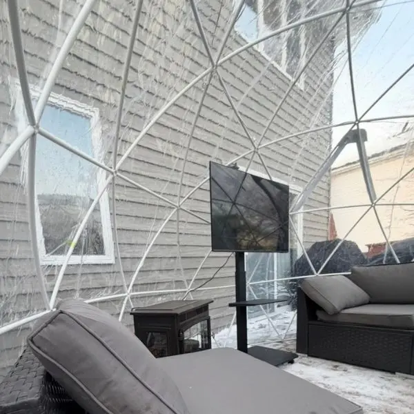 Movie night igloo rental with lounge seating and TV setup inside a clear outdoor dome