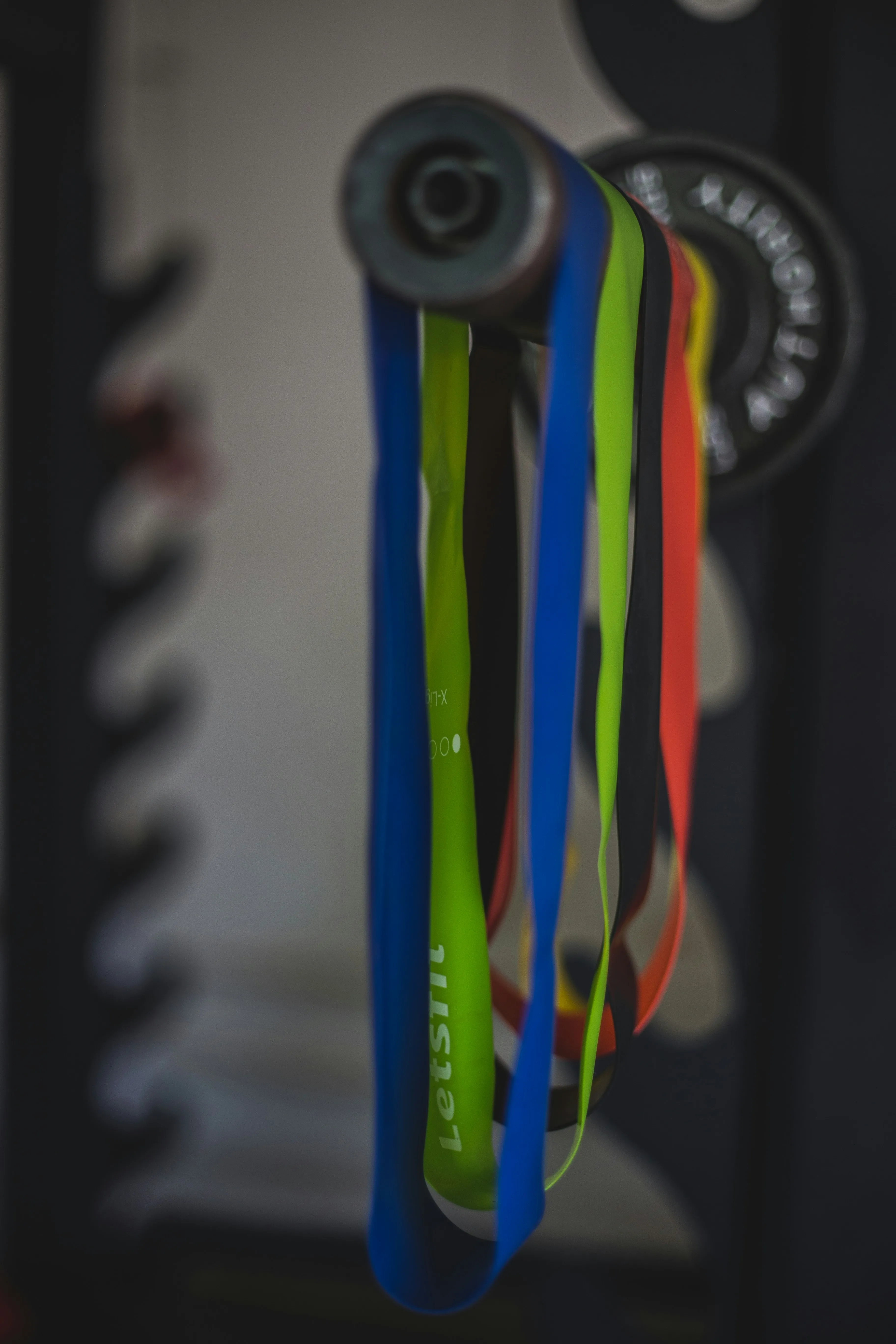 a set of colorful resistance bands hanging on a barbell