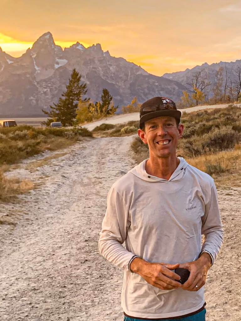 Travis poses for a portrait with the Teton mountain range in the background.
