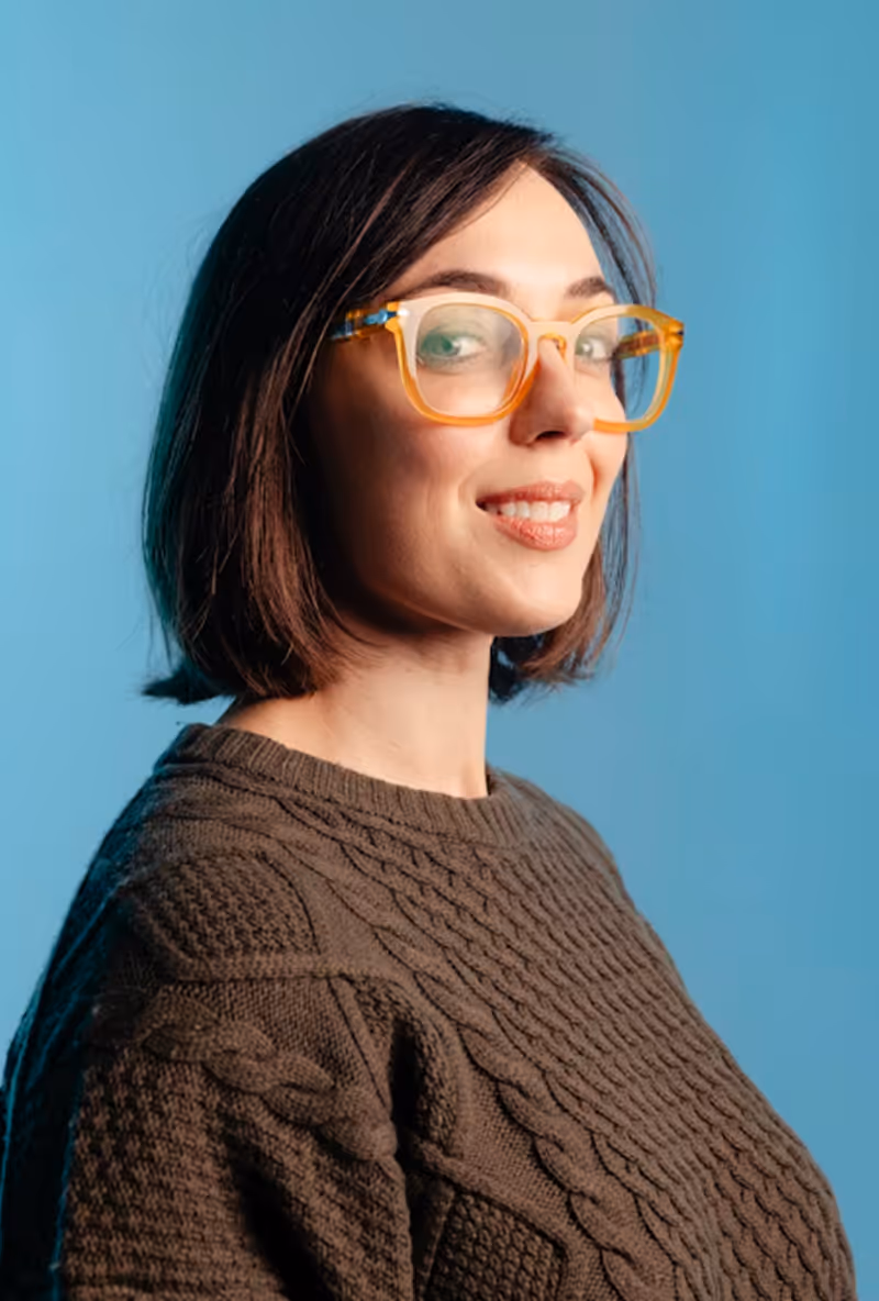 A woman wearing glasses and a brown sweater.