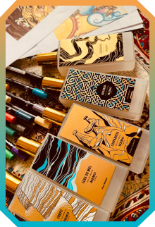 Collection of colorful perfume sample cards with artistic designs displayed on a patterned surface.