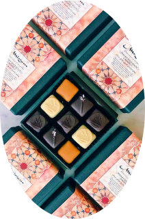 Open box of assorted chocolates surrounded by closed boxes with floral patterned lids.