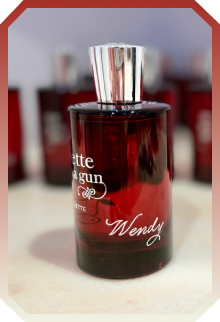 Dark red perfume bottle labeled 'Wendy' with a reflective silver cap on a light surface.