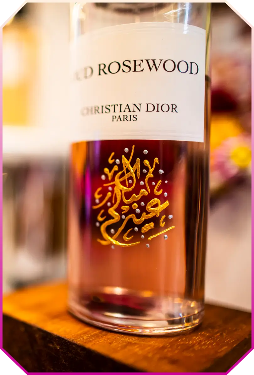 Close-up of a Dior perfume bottle labeled 'Old Rosewood' with decorative Arabic script on the glass.