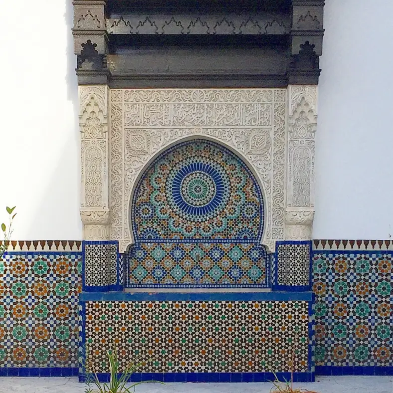 Ornate Moroccan-style wall fountain adorned with intricate geometric tile patterns and carved plasterwork.