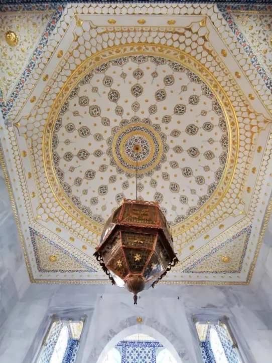 Ornate octagonal ceiling with intricate gold and blue patterns and a large traditional lantern hanging in the center.