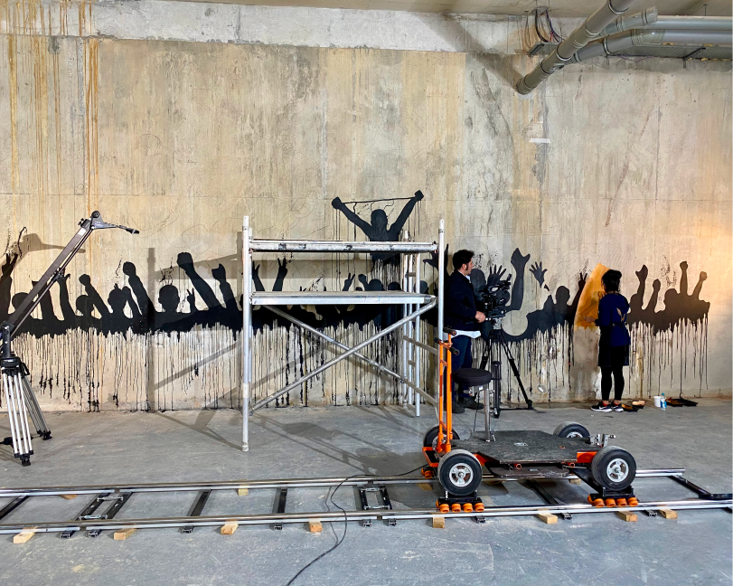 Wide view of a large mural project with scaffolding and camera dolly tracks in a studio.