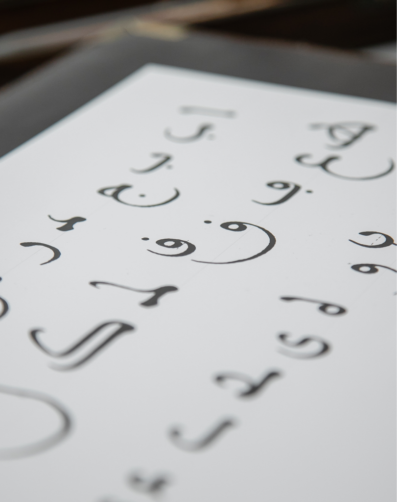 Close-up of a sheet of paper featuring elegant Arabic calligraphy characters written in black ink.