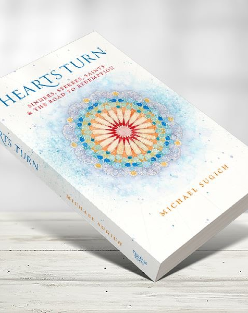 A perspective view of the book "Hearts Turn" by Michael Sugich. The white cover features a colorful, circular kaleidoscope-style mandala in the center.
