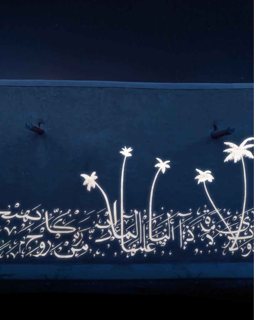 A light projection on a building facade depicting several slender, glowing white palm trees clustered together against the dark night sky.