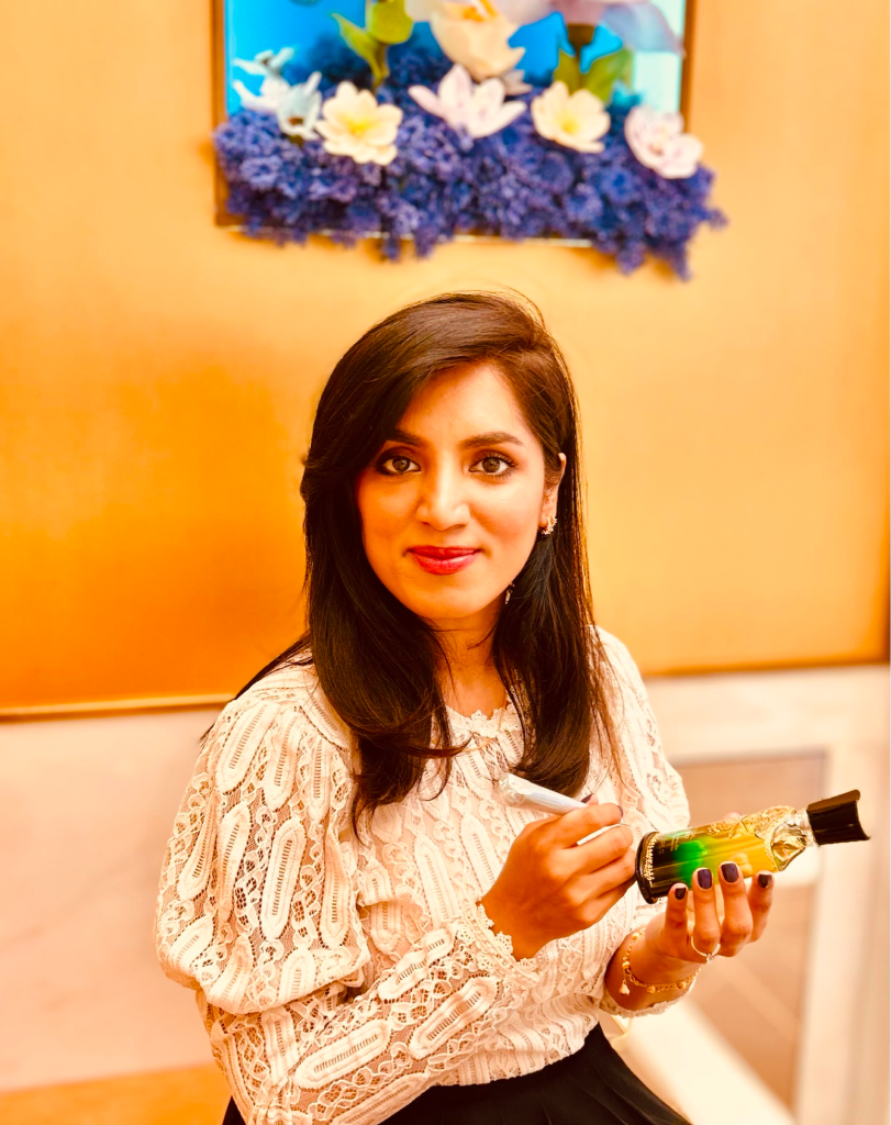 Maadia Noor at Harvey Nichols next to a digital screen announcing a luxury Creed fragrance residency.