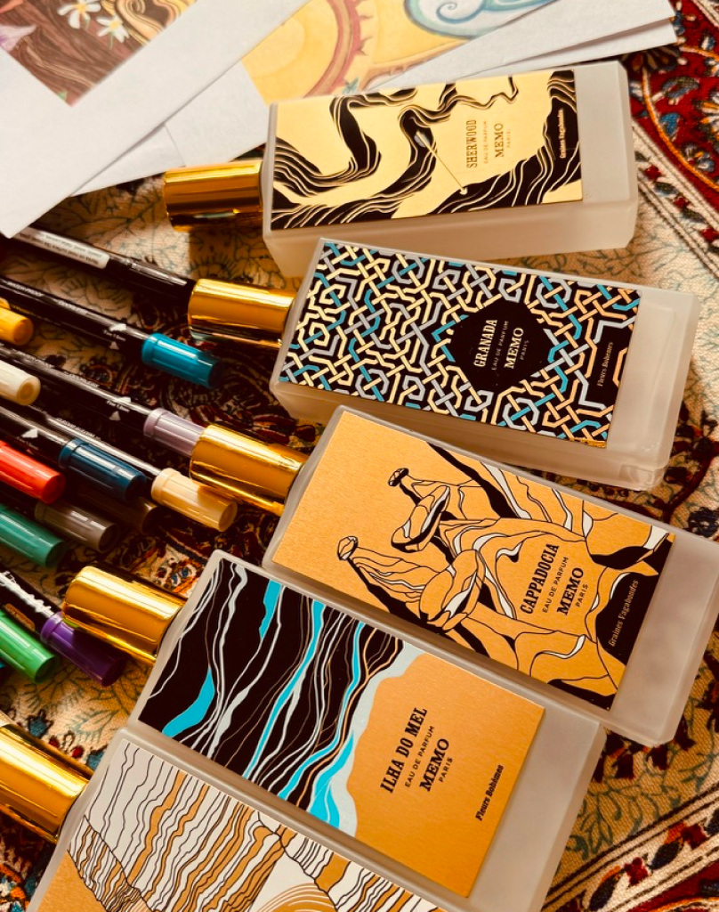 Grouping of perfume bottles with intricate gold, black, and blue geometric labels next to art markers.