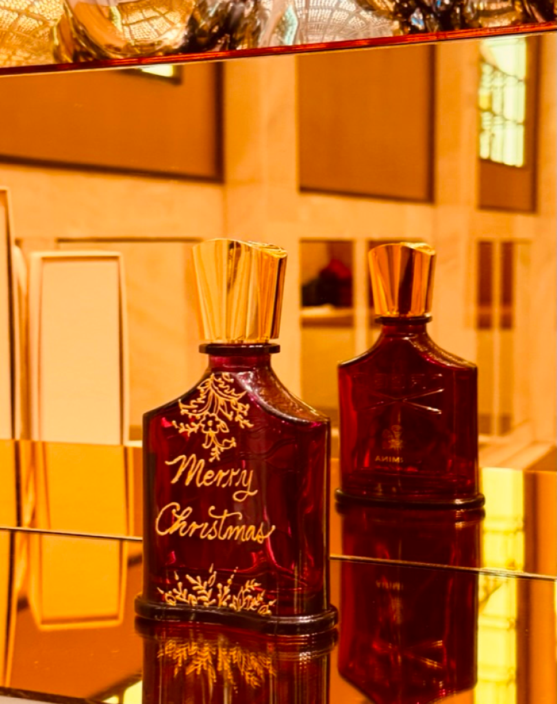 Calligrapher Maadia Noor personalizing a Creed fragrance bottle with hand-painted gold details.